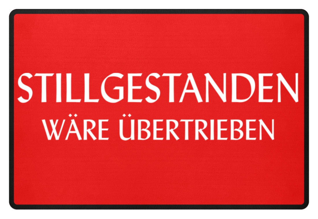Stillgestanden wäre übertrieben Fußmatte mit rotem Motiv und weißer Schrift Rechteckige Fußmatte mit roter Fläche, schwarzem Rand und großem weißen Schriftzug „Stillgestanden wäre übertrieben“ auf der Vorderseite.
