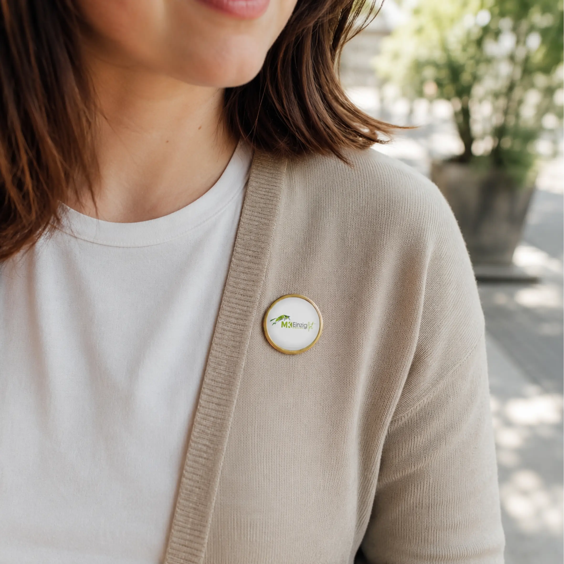 Expressabzeichen rund 28mm gold mit individuellem Motiv Rundes Expressabzeichen in Goldoptik mit weißer Motivfläche und individuellem Logo, an einer beigefarbenen Strickjacke getragen.