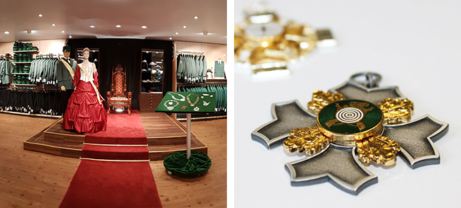 Ausgestellte Orden und Ballkleid in einem Trachtengeschäft Innenraum eines Trachtengeschäfts mit rotem Teppich, Schaufensterpuppen in Trachtenkleidung und Nahaufnahme mehrerer Orden mit grün-goldenen Details auf weißem Untergrund