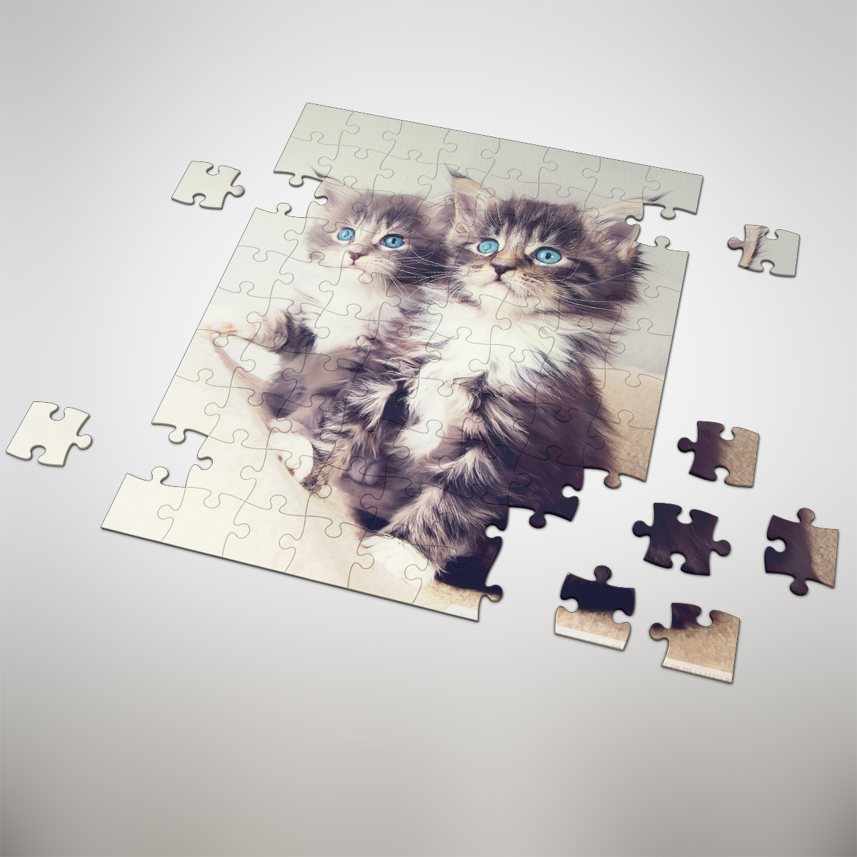 Fotopuzzle als Gutschein mit 35 Puzzleteilen und Katzenmotiv Teilweise zusammengesetztes Fotopuzzle als Gutschein mit 35 Puzzleteilen, bedruckt mit dem Motiv von zwei flauschigen Katzen mit blauen Augen; mehrere lose Puzzleteile liegen daneben.