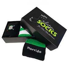 Hauptprodukt mit erweiterten Preisen – schwarze Sockenverpackung mit grün-schwarzen Socken Schwarze Verpackung mit Aufdruck „socks“ und ein Paar grün-schwarze Socken mit weißem Schriftzug „Horrido“, passend zum Hauptprodukt mit erweiterten Preisen.