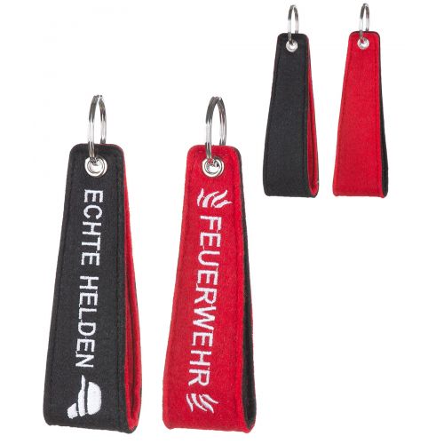 Filz Schlüsselanhänger Feuerwehr/Echte Helden in Schwarz und Rot Schwarz-roter Filz Schlüsselanhänger mit Metallring, auf einer Seite mit ECHTE HELDEN und auf der anderen mit FEUERWEHR in Weiß bestickt, in schmaler rechteckiger Form.