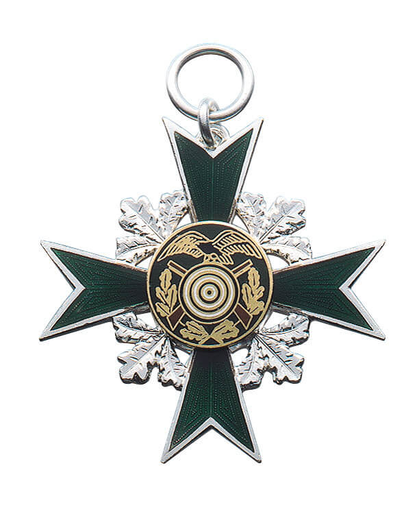 Orden versilbert, grünes Kreuz mit Eichenlaub und Zielscheibe mit Adler Versilberter Orden in Kreuzform mit grünen Armen, Eichenlaubkranz und runder Auflage mit Zielscheibe, Adler und Gewehren