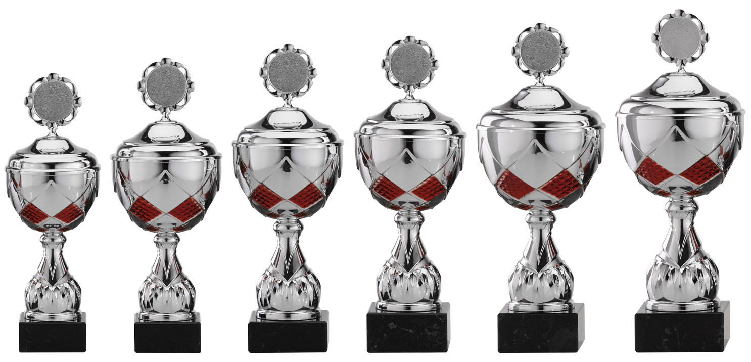 Sechs silberfarbene Pokale mit rotem Rautenmuster auf schwarzem Sockel Sechs Pokale in unterschiedlicher Größe, silberfarben mit Deckel, rundem Emblem oben, rotem Rautenmuster am Korpus und schwarzem Sockel