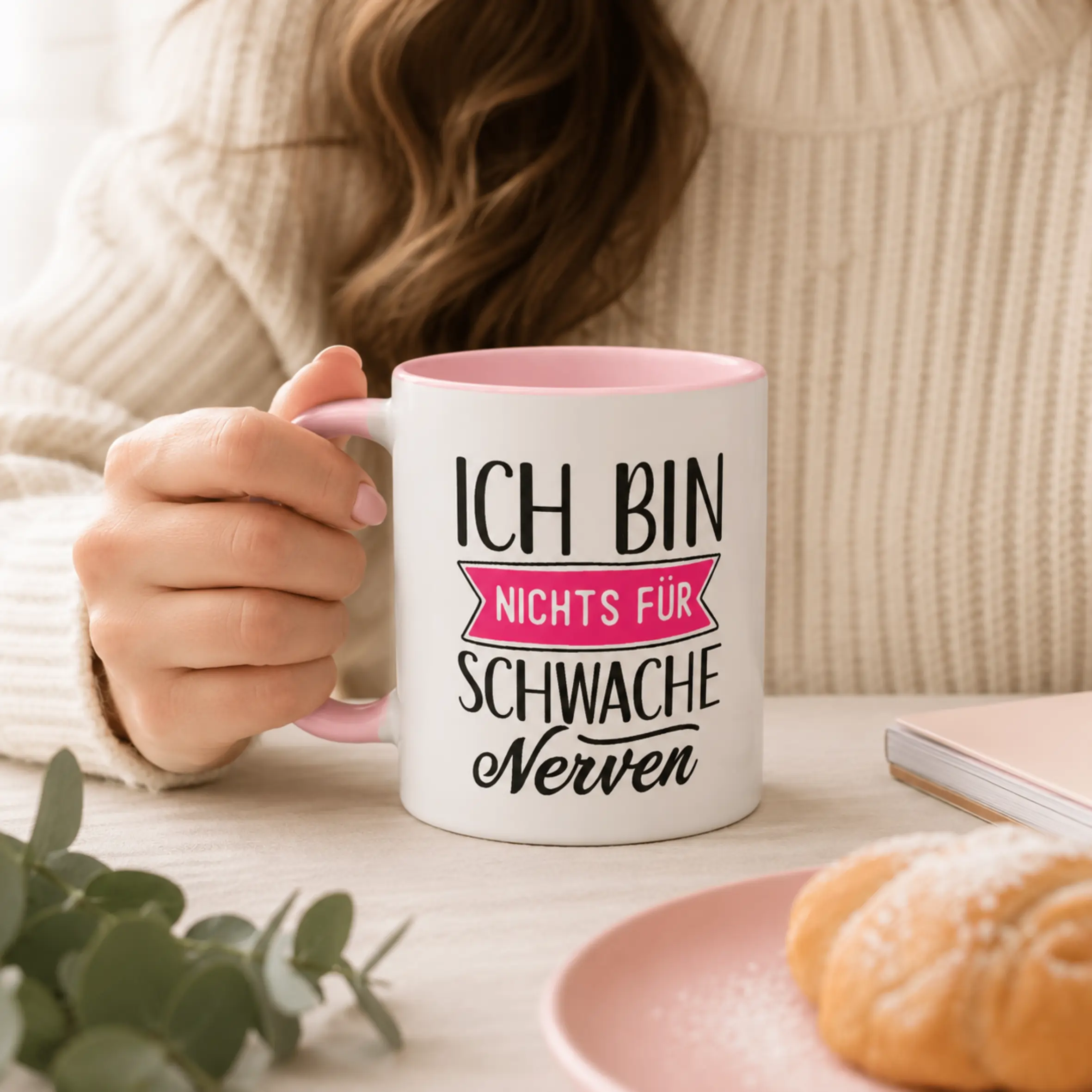 Tasse Ich bin nichts für schwache Nerven mit rosa Henkel und rosa Innenseite Weiße Tasse mit rosa Innenseite und rosa Henkel, bedruckt mit dem Spruch „Ich bin nichts für schwache Nerven“, in einer Hand gehalten.