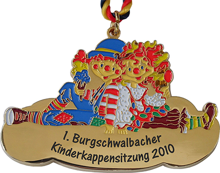 Goldfarbener Karnevalsorden „Clown-Pärchen“ mit zwei bunt gestalteten, sitzenden Clowns an einer rot-gelb-blauen Kordel. Das goldfarbene Schriftfeld trägt „1. Burgschwalbacher Kinderkappensitzung 2010“.