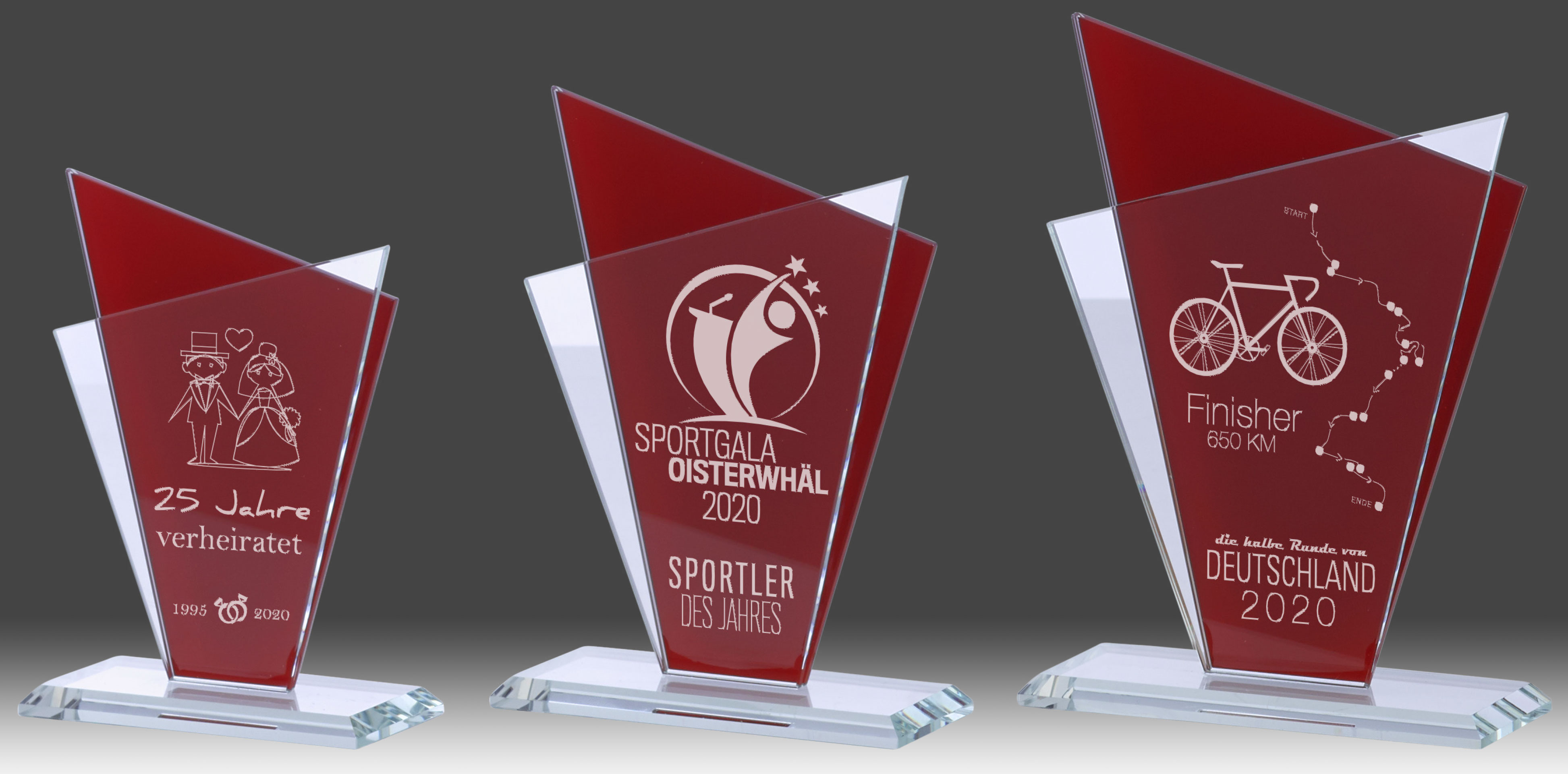 Glasständer eckig, rot und doppelt mit Sockel Drei eckige Glasständer mit roter Doppelscheibe und klarem Glassockel, jeweils mit individueller Gravur als Beispiel für die Veredelung.