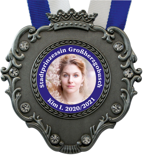 Prinzenpaar-Orden in Antiksilber mit geprägter Krone, geschwungenen Verzierungen und klaren Glitzersteinen am blau-weißen Halsband. Mittig ein Frauenporträt mit blauem Schriftring „Stadtprinzessin Großherzog Busch – Kim I. 2020/2021“., Medaille, Kunstsamm