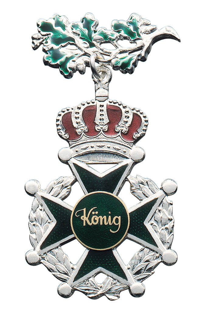Orden mit Eichenlaub und roter Krone Silberfarbener Orden mit grünem Eichenlaub oben, roter Krone, silbernem Eichenlaubkranz und grünem Kreuz mit runder Mittelauflage "König".
