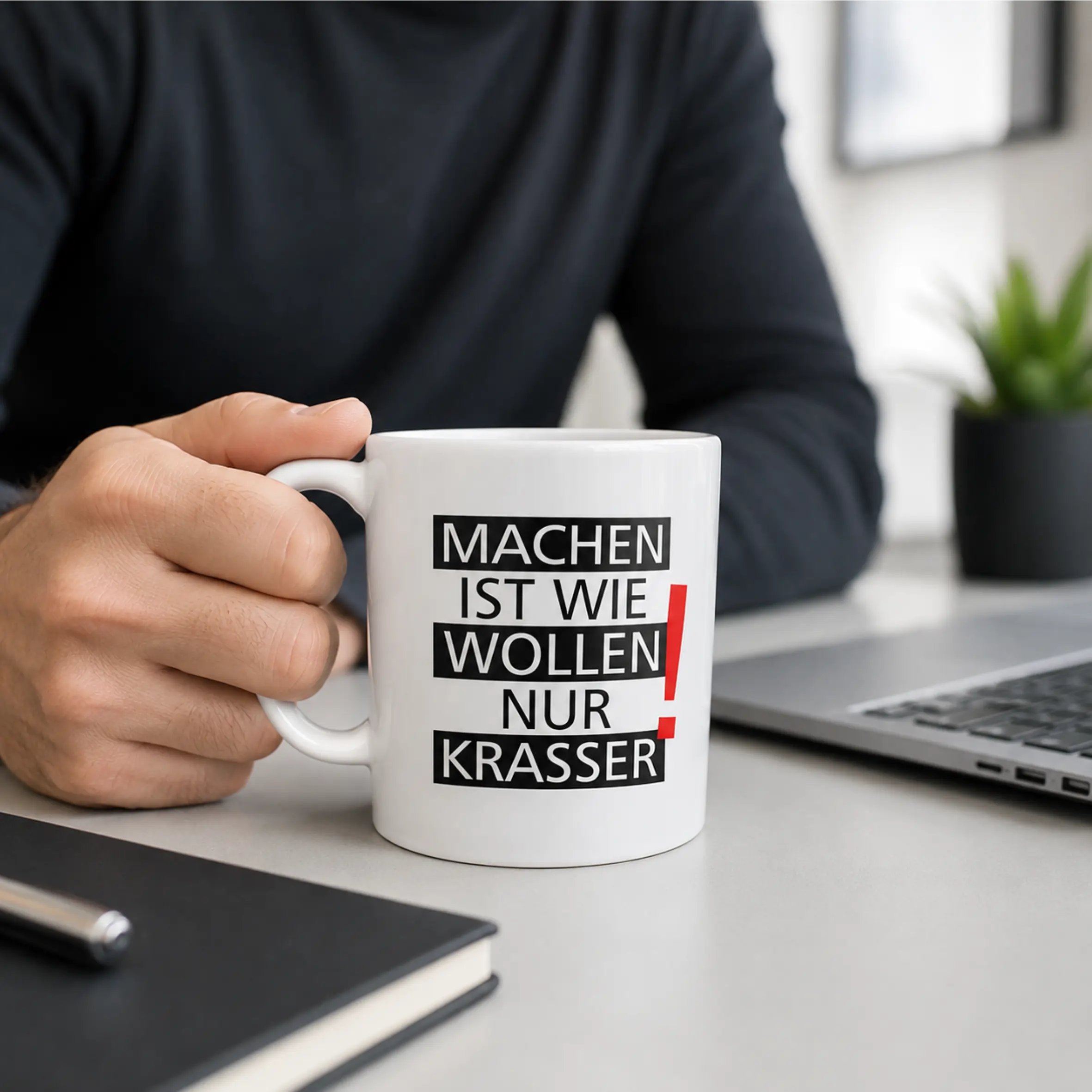 Tasse Machen ist wie wollen nur krasser mit schwarz-rotem Schriftmotiv Weiße Keramiktasse mit C-Henkel und dem Aufdruck „Machen ist wie wollen nur krasser“ in schwarzer Schrift mit rotem Ausrufezeichen, auf einem Schreibtisch neben Laptop und Notizbuch.