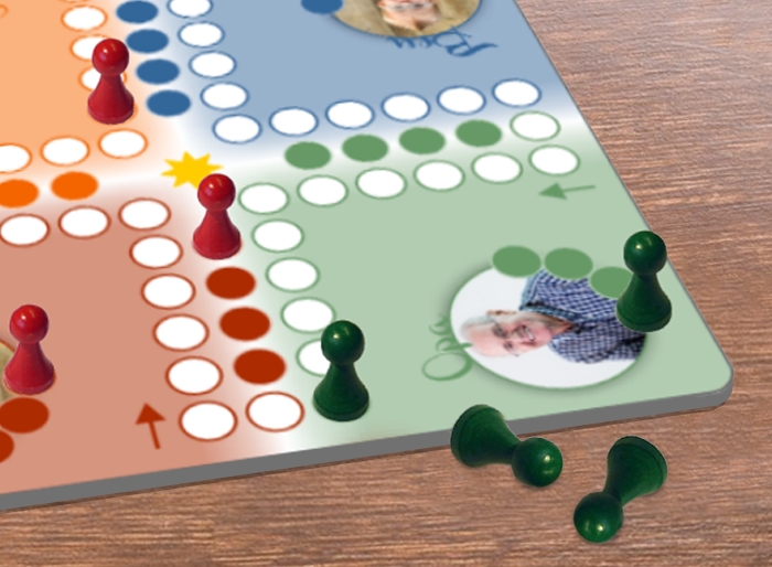 Mensch-ärgere-dich-nicht-Spielbrett mit roten und grünen Spielfiguren Ausschnitt eines Mensch-ärgere-dich-nicht-Spielbretts auf Holztisch mit roten und grünen Spielfiguren, farbigen Feldern und zwei grünen Figuren neben dem Brett