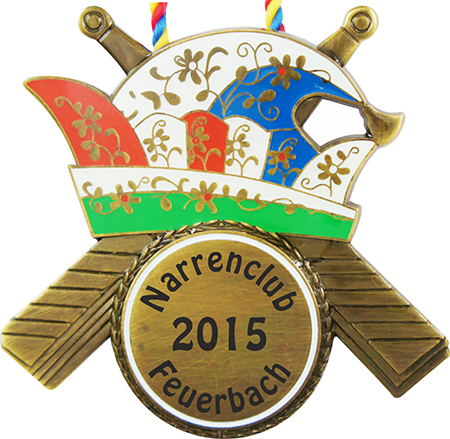 Karnevalsorden in Antikbronze-Optik mit bunt gestalteter Komiteemütze und zwei gekreuzten Paddeln. Rundes Mittelfeld mit der Aufschrift „Narrenclub 2015 Feuerbach“, oben eine rot-gelb-blaue Kordel.