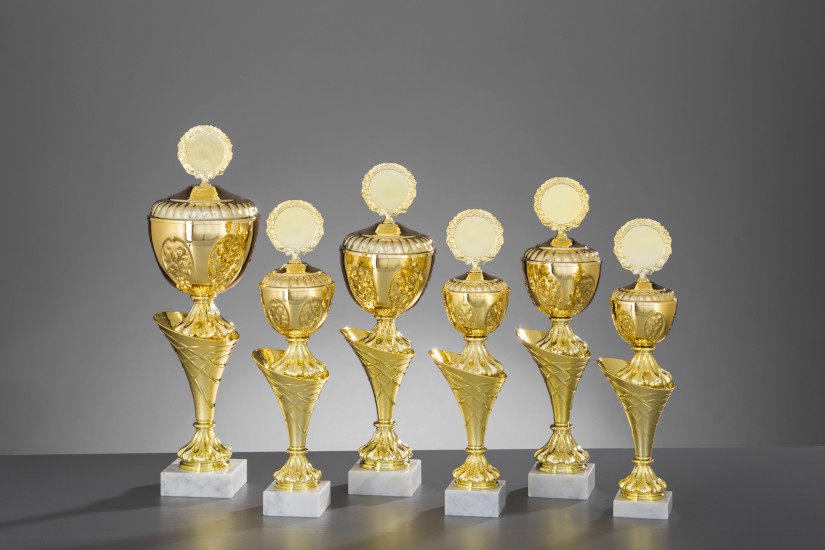 6er Pokal Serie Glenda gold von EinzigArt Sechs goldfarbene Pokale der Serie Glenda von EinzigArt in unterschiedlichen Höhen, mit rundem Emblemhalter, kelchförmigem Oberteil und weißem Sockel.
