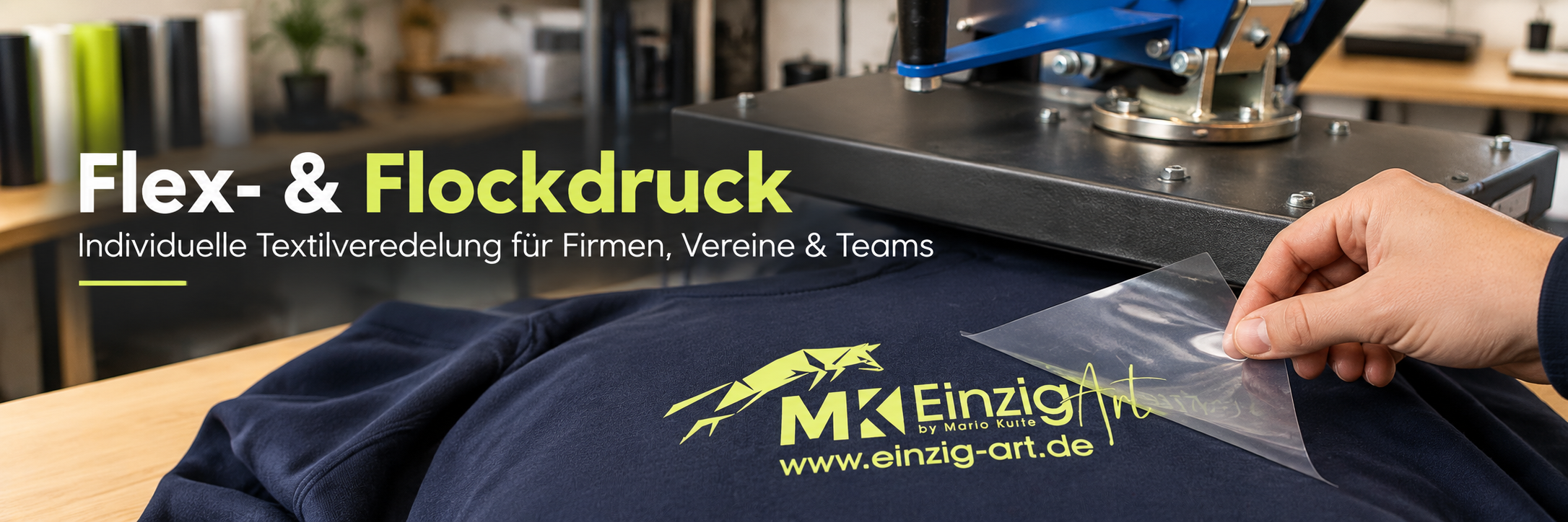 Flex- und Flockdruck: Textilveredelung an der Transferpresse Eine Hand zieht transparente Transferfolie vom gelbgrünen EinzigArt-Logo auf einem dunkelblauen Textil ab. Dahinter steht eine Transferpresse. Aufschrift: „Flex- & Flockdruck – Individuelle Textilveredelung für Firmen, Vereine & Teams“.