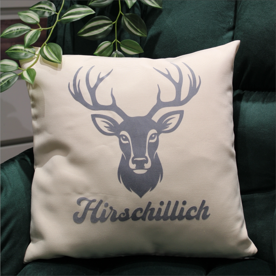 Dekokissen Hirschillich 40x40 cm mit Hirschmotiv in Hellgrau Cremefarbenes Dekokissen 40x40 cm mit hellgrauem Hirschkopf und dem Schriftzug „Hirschillich“ auf der Vorderseite.