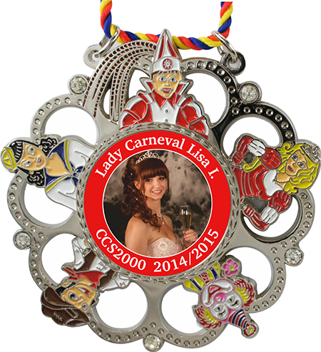 Silberfarbener Karnevalsorden mit fünf Glitzersteinen, Aussparungen und bunten Narrenfiguren an rot-gelb-blauer Kordel. Mittig ein Frauenporträt mit rotem Rand und der Aufschrift „Lady Carneval Lisa I. CCS2000 2014/2015“.