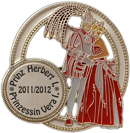 Prinzenpaar-Abzeichen Silber mit Aussparung und rundem Druckfeld Prinzenpaar-Abzeichen in Silber mit Aussparung, rundem Druckfeld und Darstellung eines Prinzenpaares in Rot und Silber. Der Pin ist aus Metall mit silberfarbener Kontur und kreisförmigem Rahmen gestaltet.