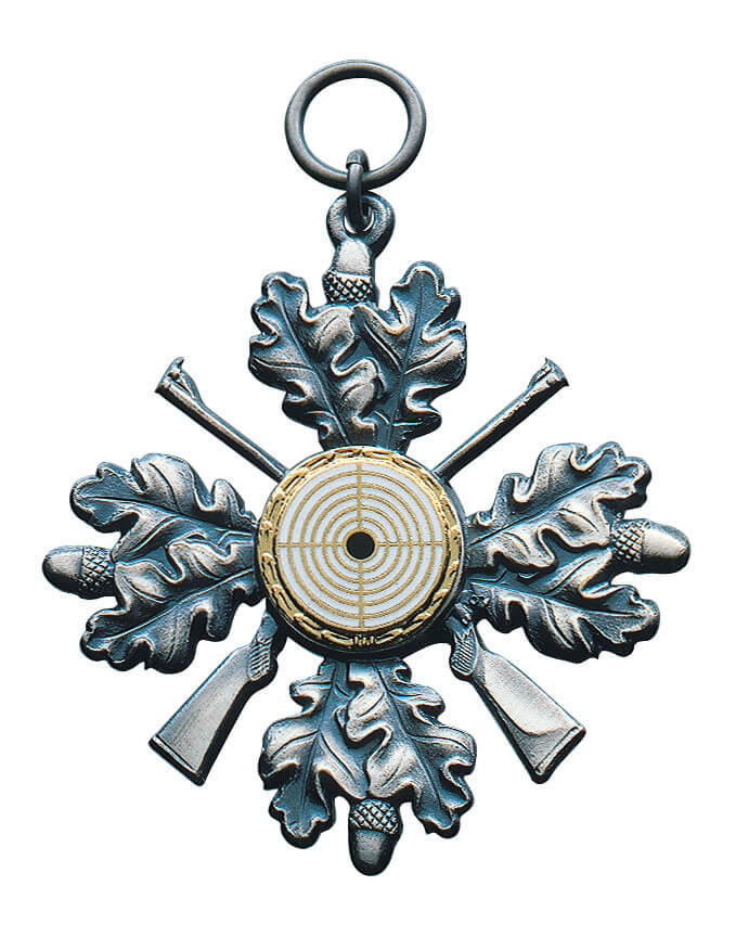 Orden altsilber mit Eichenlaub, gekreuzten Gewehren und Zielscheiben-Auflage Orden altsilber in Eichenlaub-Form mit gekreuzten Gewehren, runder Zielscheiben-Auflage in der Mitte sowie Öse und Ring zum Anhängen